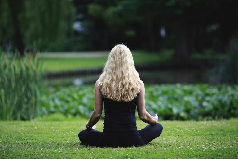 A lady sitting crossed legged in a peaceful park 